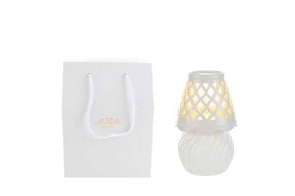 Lampada in porcellana bianca con design traforato, dimensioni 8,5×8,5×h.13,5 cm, accanto a shopper bianco elegante.