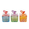 Tre candele in scatole di vetro colorato con decorazioni a farfalla, disponibili in tre colori assortiti: blu, verde e arancione.