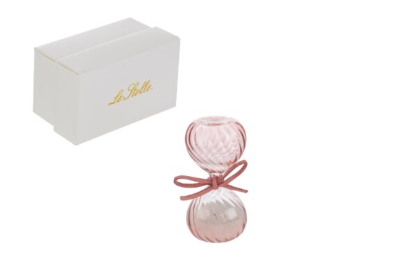 Clessidra in vetro rosa, decorata con un fiocco, accanto a un astuccio bianco elegante con scritta dorata.