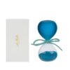Clessidra in vetro celeste satinato con sabbia blu, altezza 8 cm, accanto ad astuccio bianco.