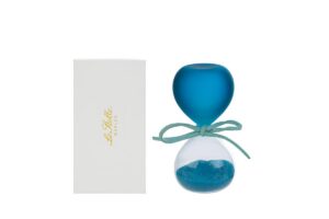 Clessidra in vetro celeste satinato con sabbia blu, altezza 8 cm, accanto ad astuccio bianco.